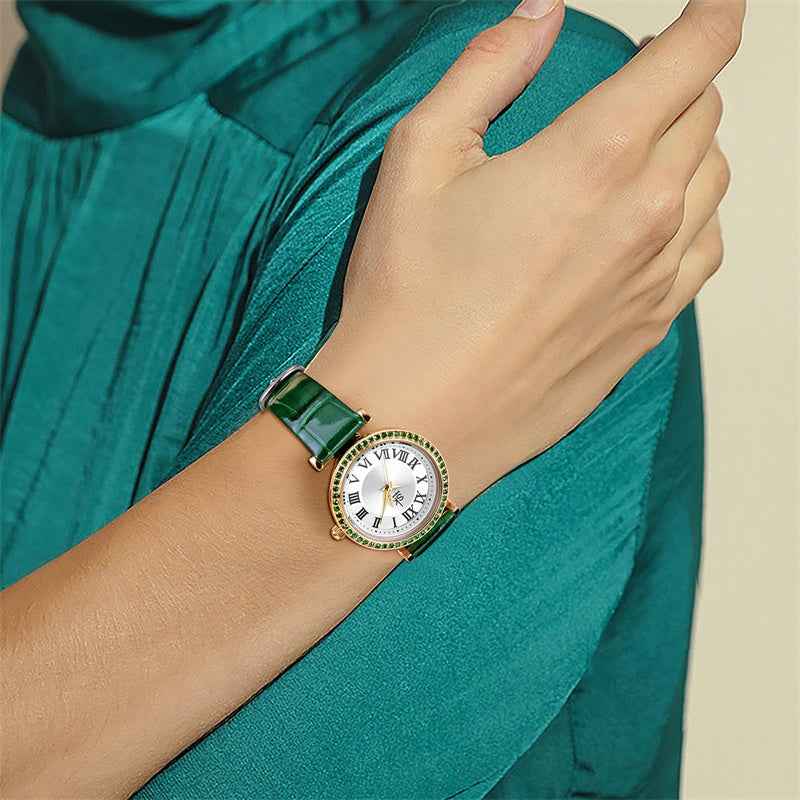 Hand wearing a green watch with a white face, set against a teal fabric background.